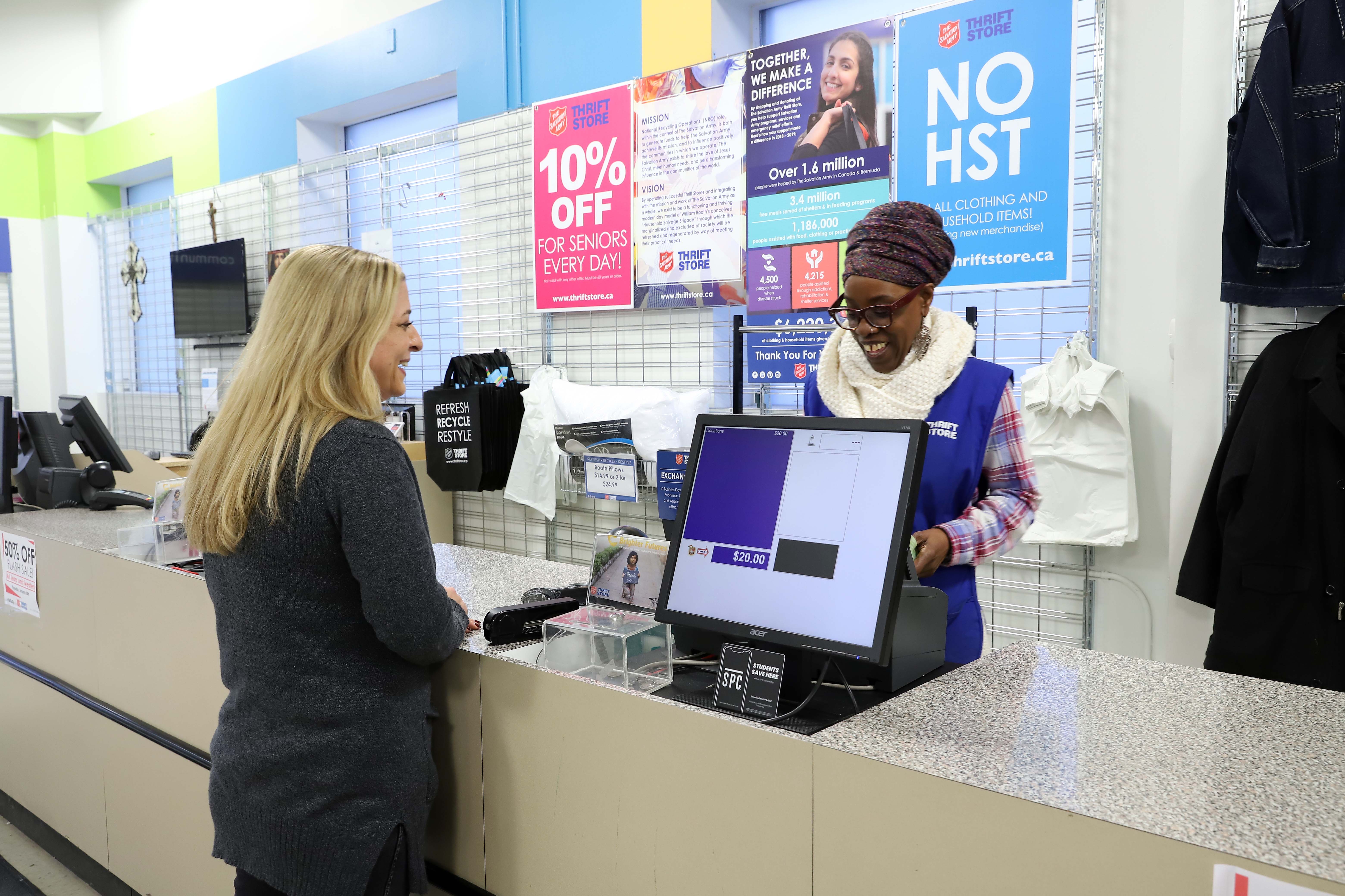 Staff member assisting a donor with a financial donation at a store counter.